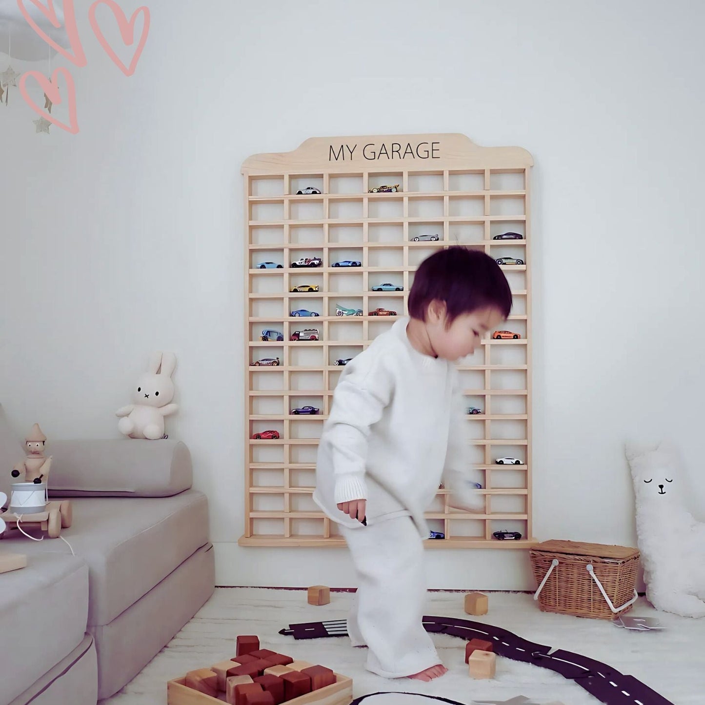 Child organizing Hot Wheels cars in a Montessori-style wooden wall rack in a calming playroom setting