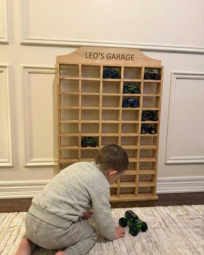 Child playing with toy cars in front of a wooden shelf labeled 'Leo's Garage'.
