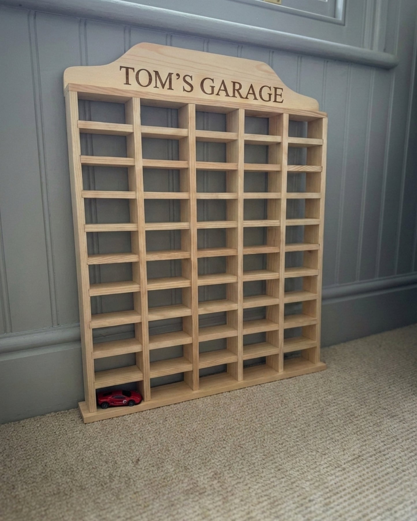 Wooden shelf with 'Tom's Garage' engraving against a gray wall.