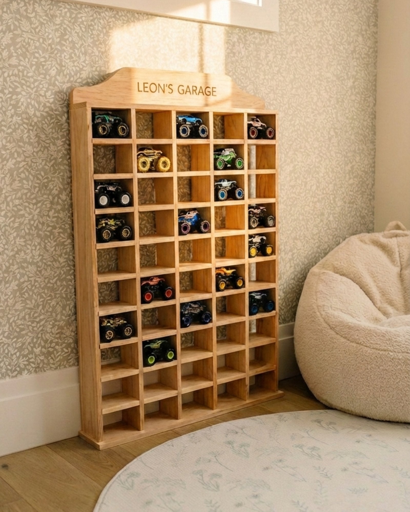 Wooden toy car garage with miniature cars inside, labeled 'Leon's Garage', in a room setting.